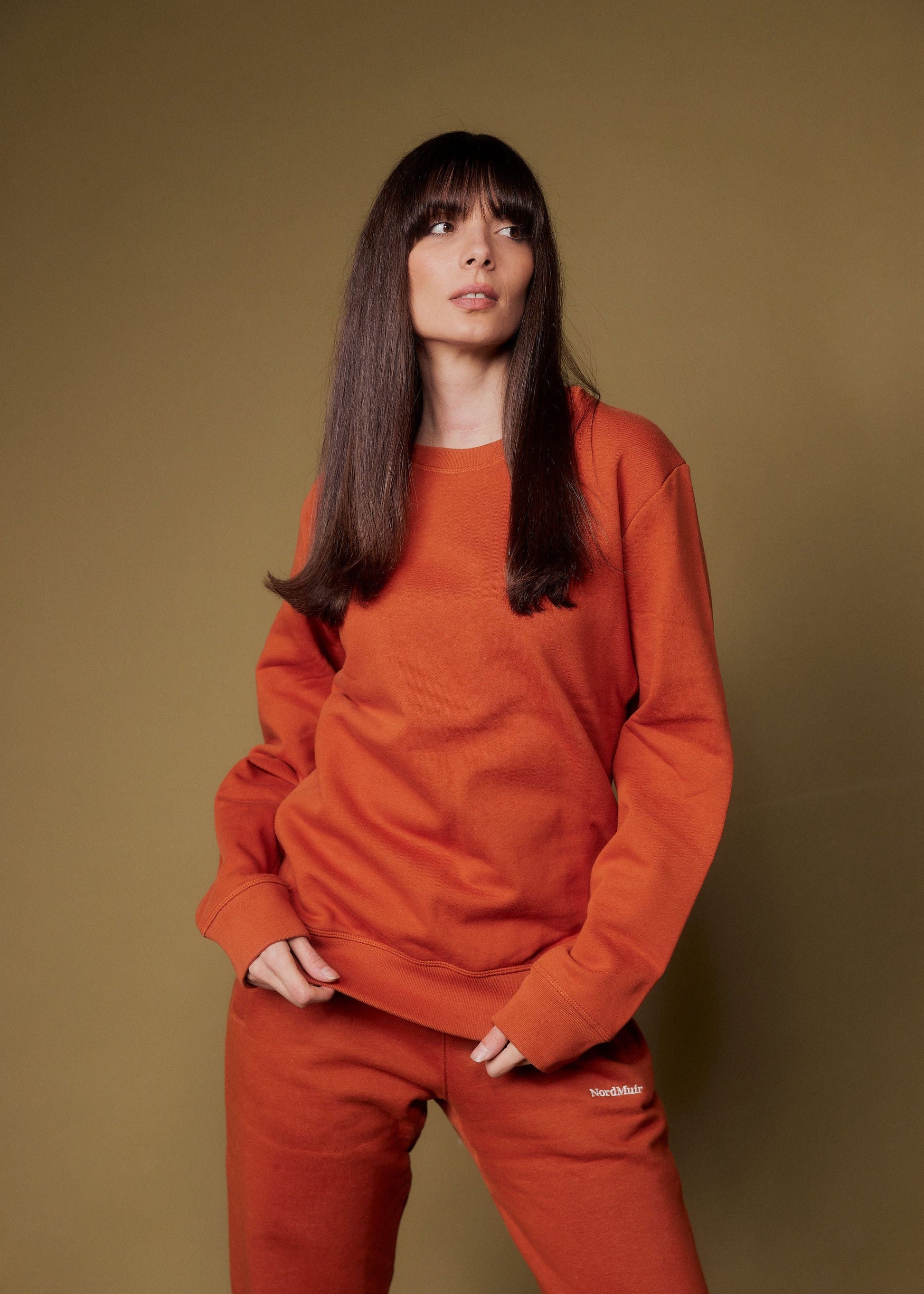 Woman wearing an orange outfit against a brown background